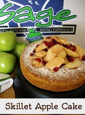 A Skillet Apple Cake topped with apple slices and dried cranberries