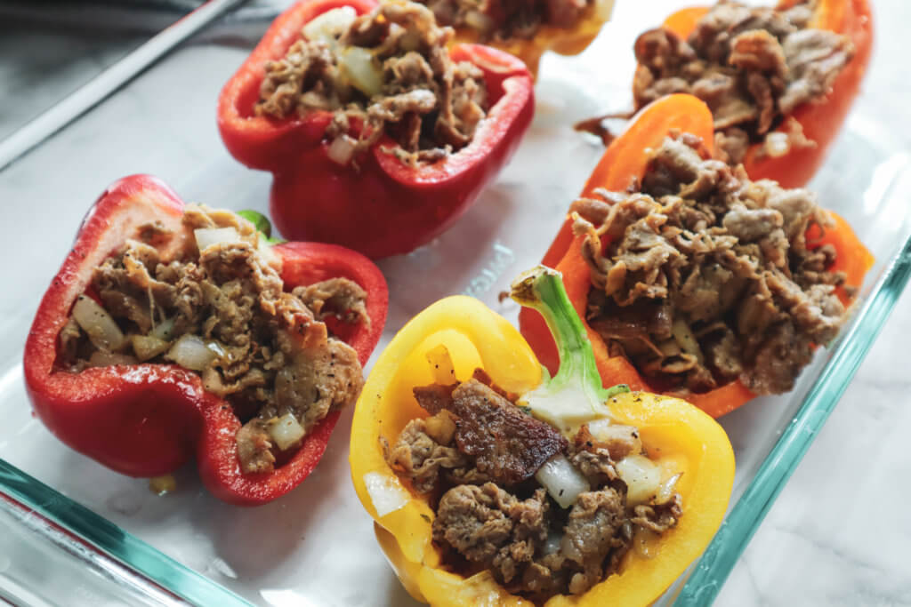 bell peppers in a glass dish stuffed with cheesesteak filling