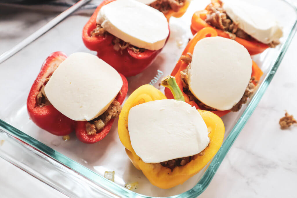 bell peppers stuffed with cheesesteak mixture and topped with mozzarella cheese in baking dish