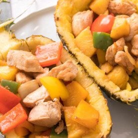 vertical close up shot of chicken and bell peppers cooked and served in a pineapple