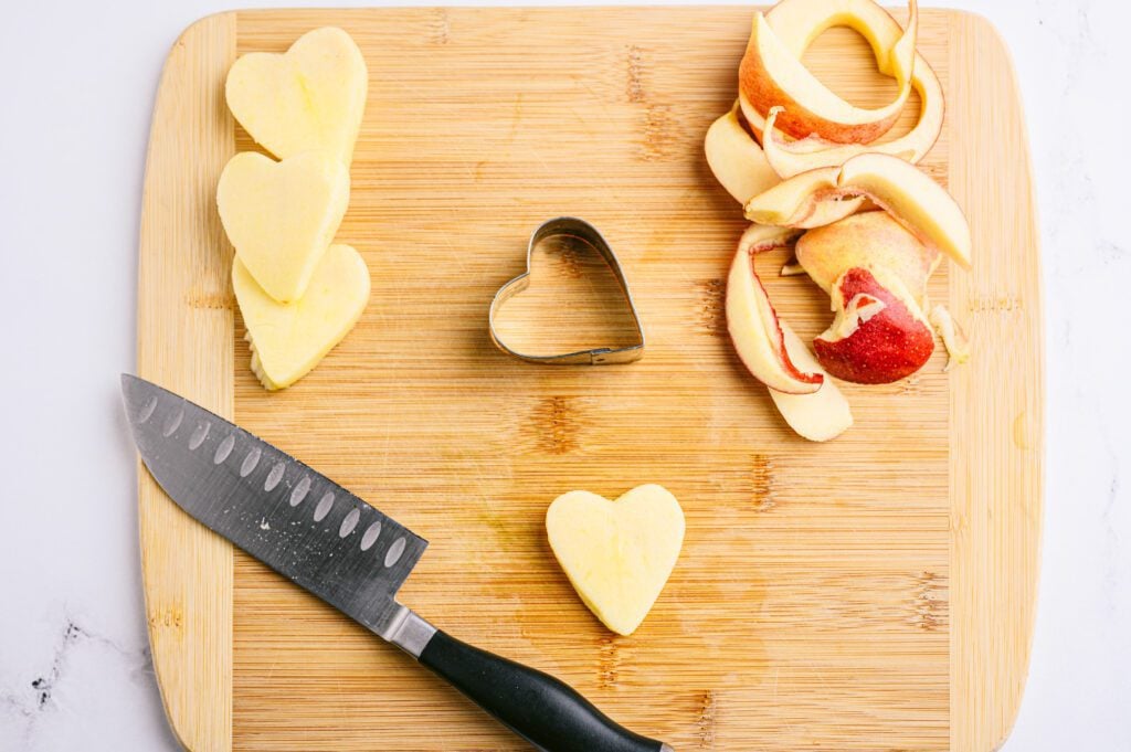 cutting board with heart cookie cutter and apples cut into hearts