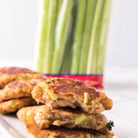 vertical image of crab cakes cut in half showing flakiness and dandy celery sticks in the background