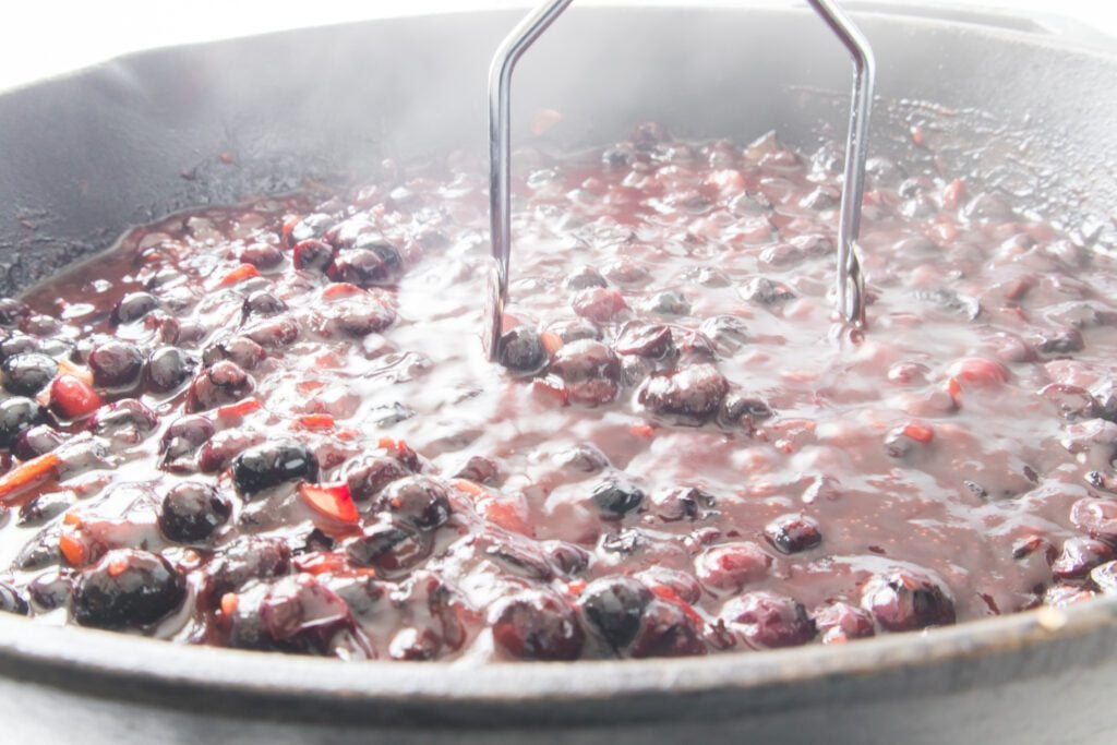 Smaching the blueberries in the skillet using a masher