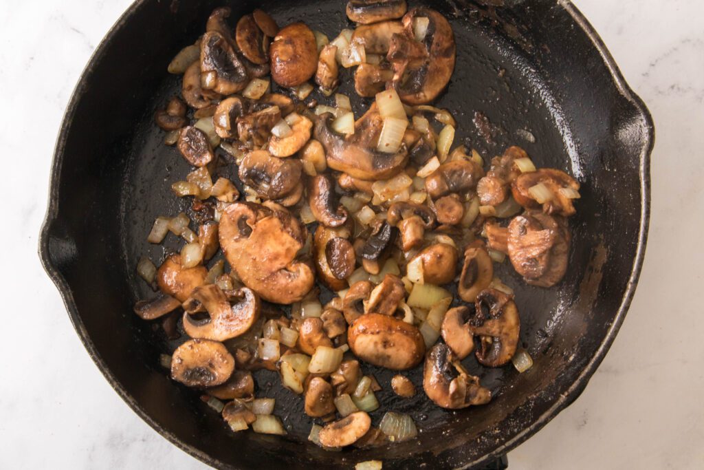 adding mushrooms and onion to skillet