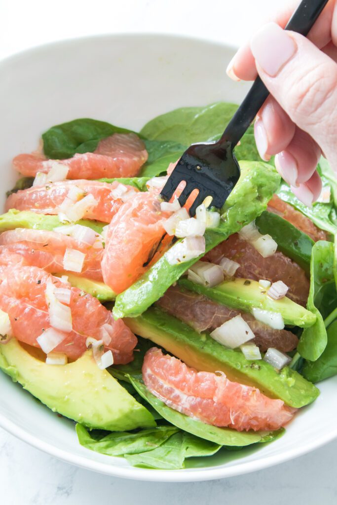 fork with avocado and grapefruit in white bowl