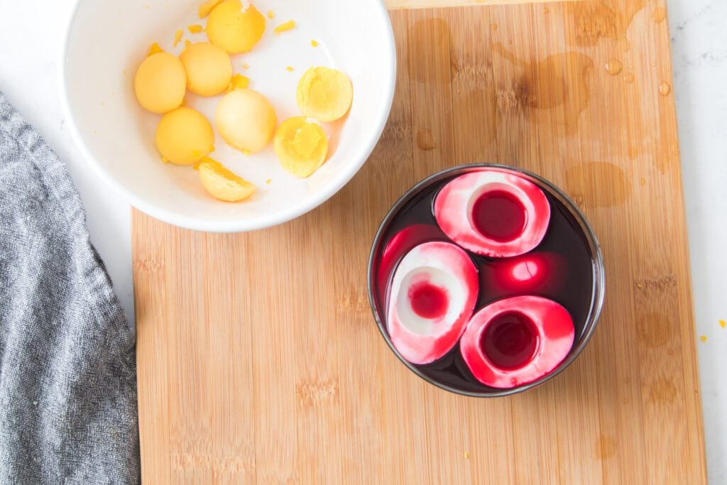 hard boiled eggs in beet juice with yolks in a bowl