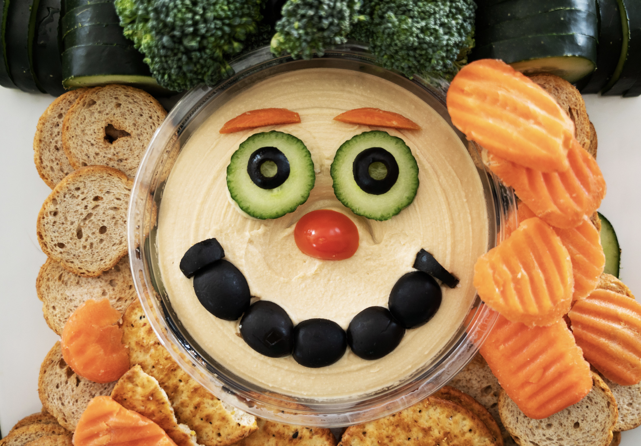 Create the leprechaun face with fresh veggies: cucumbers with olives as eyes, cherry tomato as notes and black olives as the mouth