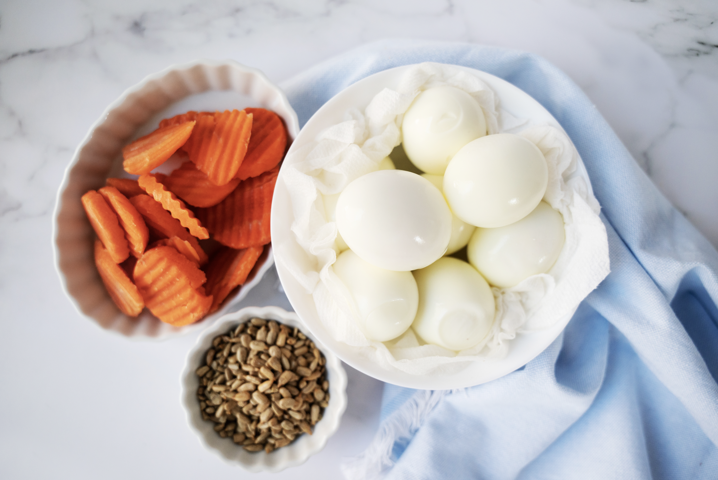 Ingredients in bowls: hard boiled eggs, carrot chips, sunflower seeds