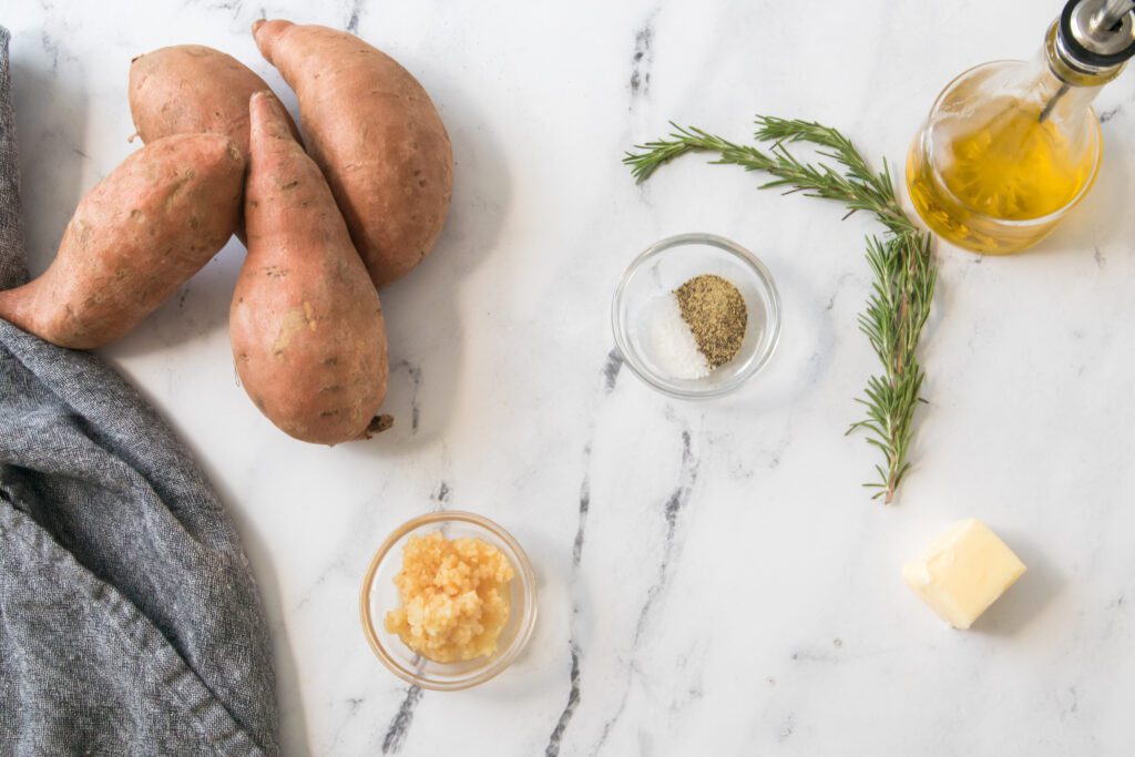 Image of the ingredients for the sweet potato bake: sweet potatoes, rosemary, oil, butter, garlic