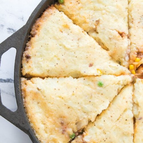 overhead vertical shot of cut slices of shepherd's pie in a cast iron skillet