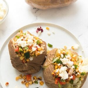 vertical overhead shot of mexican street corn baked potatoes on a white plate