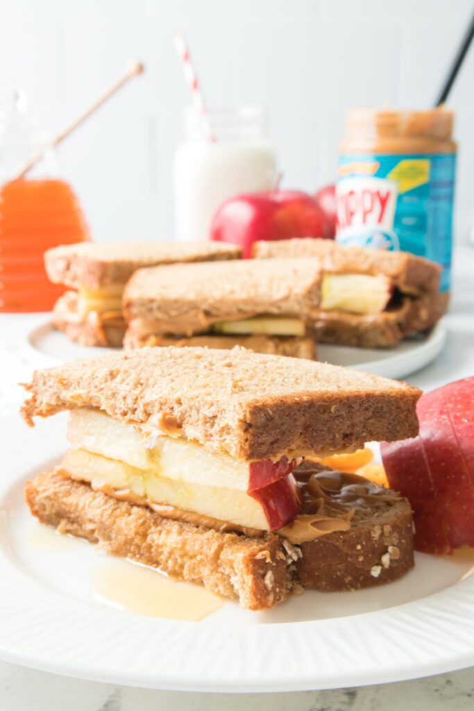 apple, peanut butter and honey sandwich on a white plate