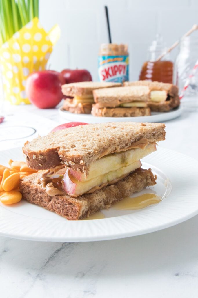 apple, peanut butter and honey sandwich on a white plate