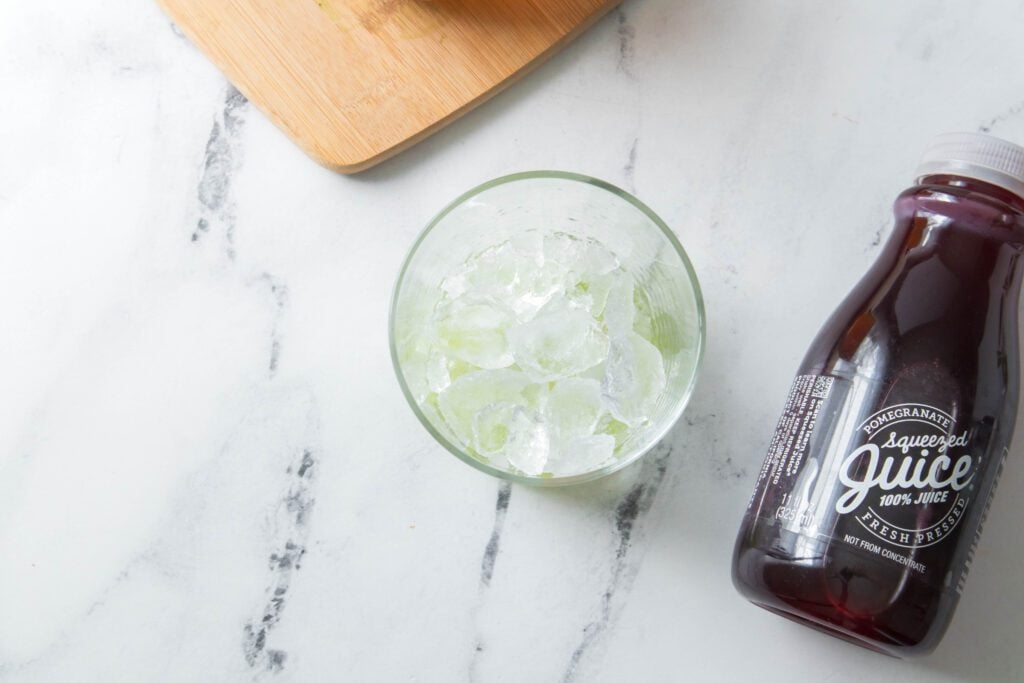 Glass of ice with cucumbers at bottom with Pomegranate Squeezed Juice