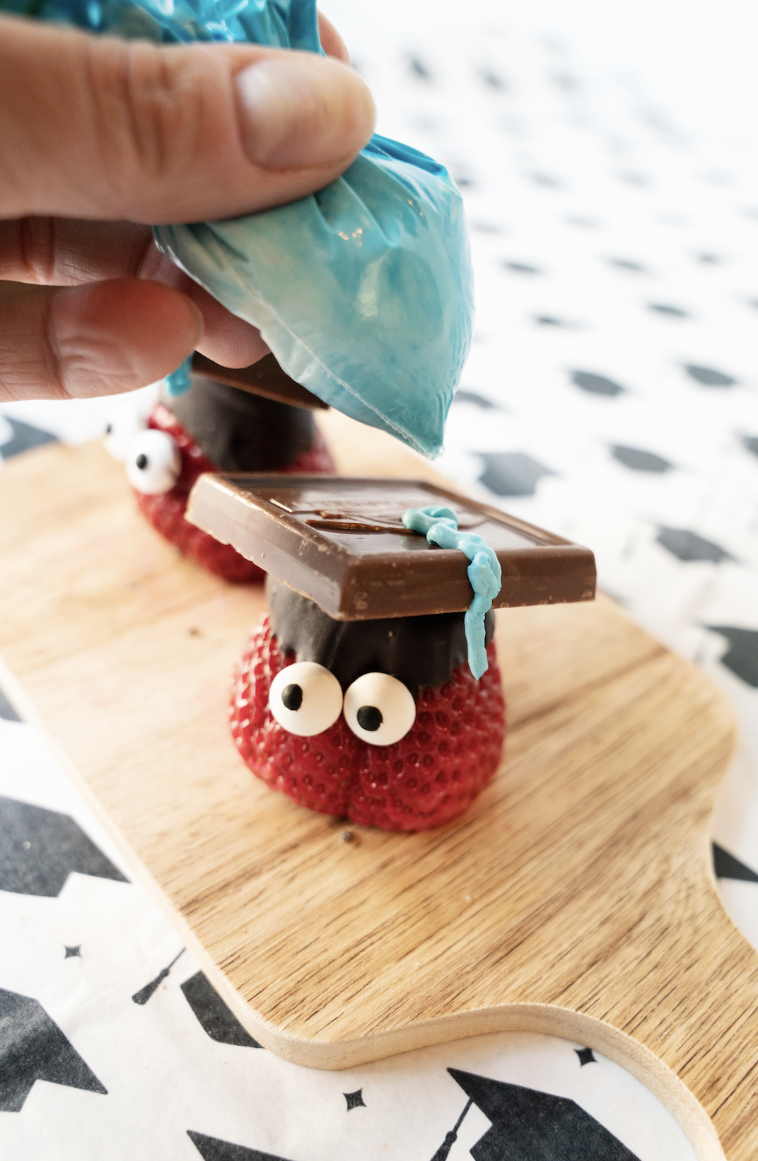 Piping the tassel on the strawberry graduation cap