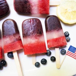 bomb pop popsicles on white serving tray with blueberries and lemon