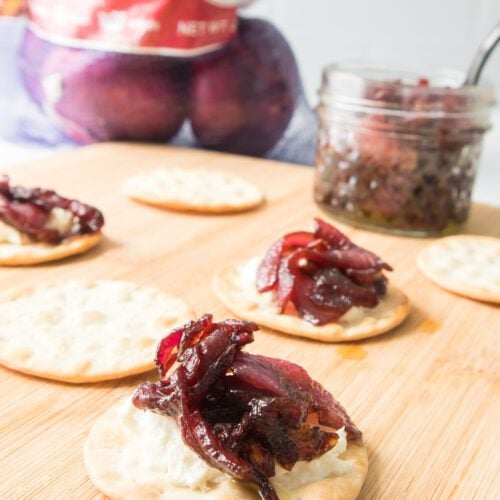 vertical shot of red onion marmalade on cracker with cheese