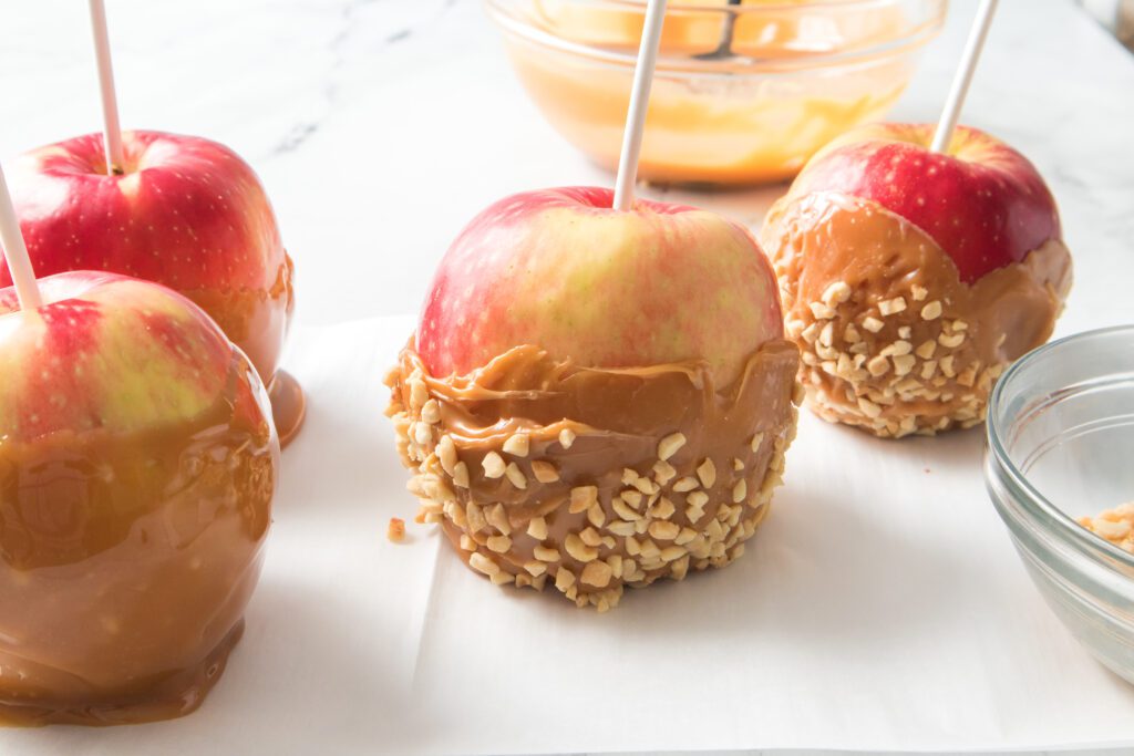 4 apples after being dipped in caramel and nut toppings