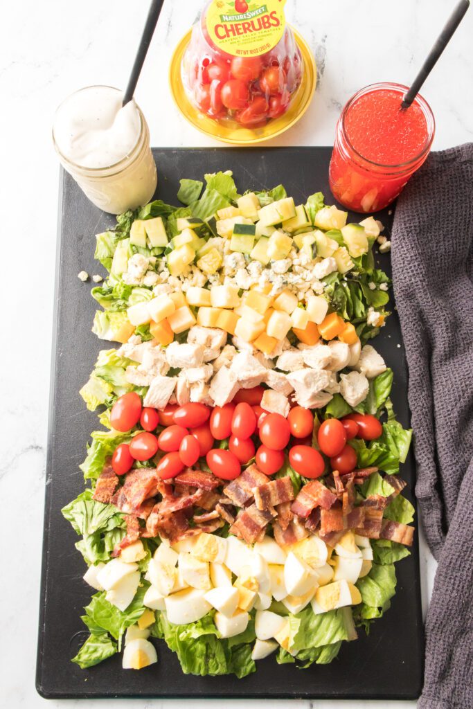 cobb salad on a serving board with ranch and red wine dressing