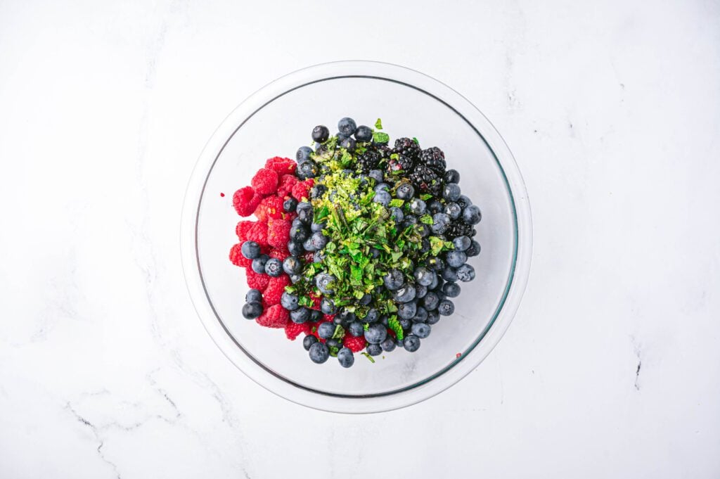 Wash and dry your berries and add them to a large mixing bowl. Add your lime zest, lime juice, and mint to your berries.
