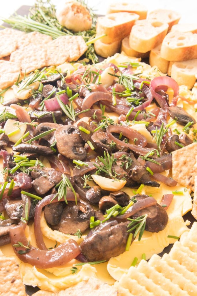 close up shot of mushroom and onion butter board with crackers and bread