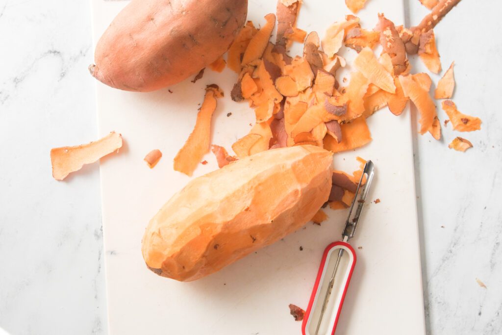 sweet potatoes peeled on a cutting board