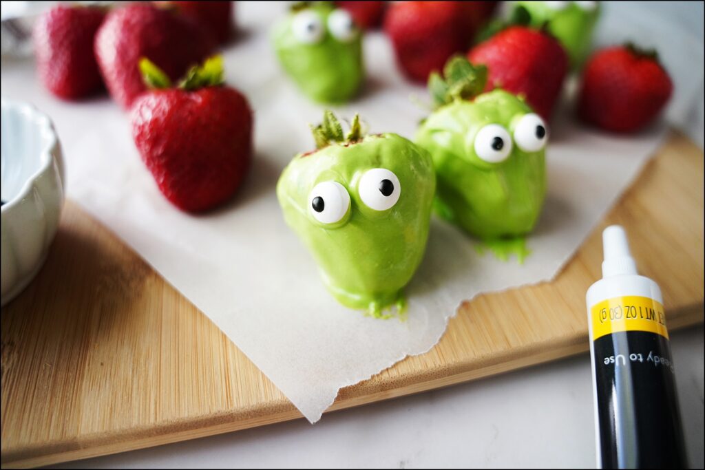 candy eyes being added to a frankenstein inspired strawberry