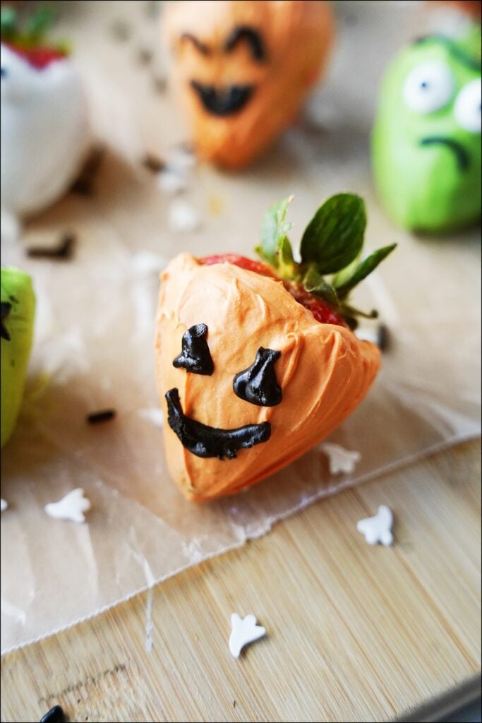 close up shot of halloween strawberry made to look like a pumpkin