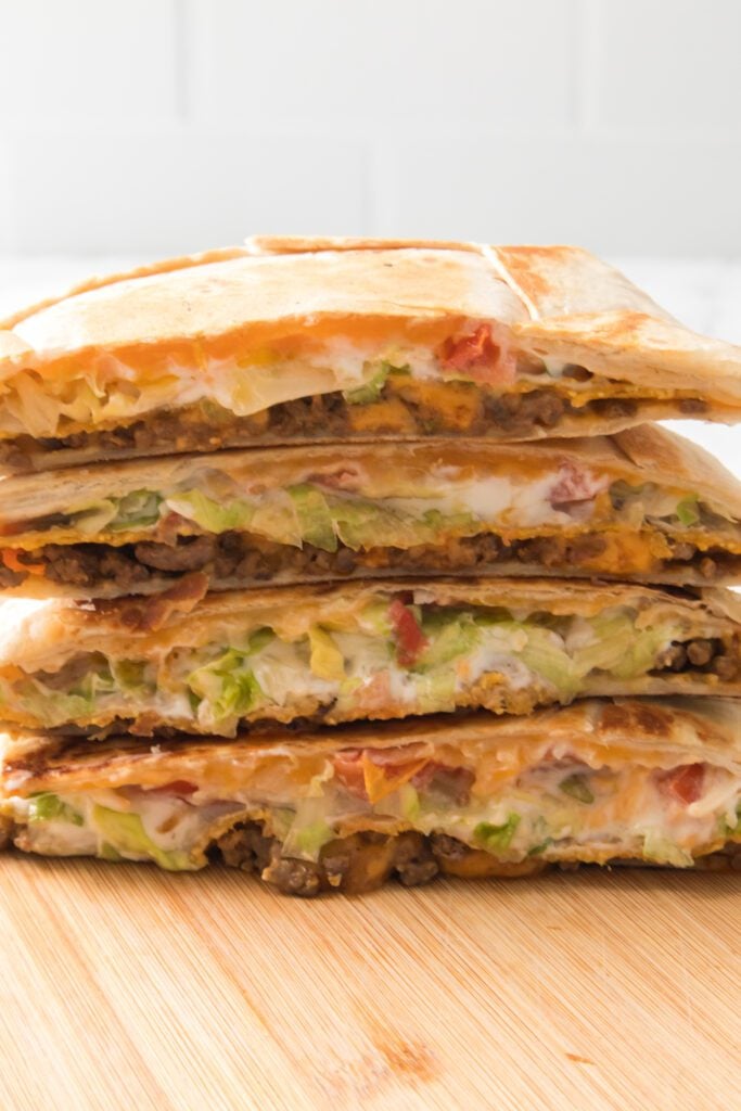 crunchwraps stacked on top of one another on cutting board