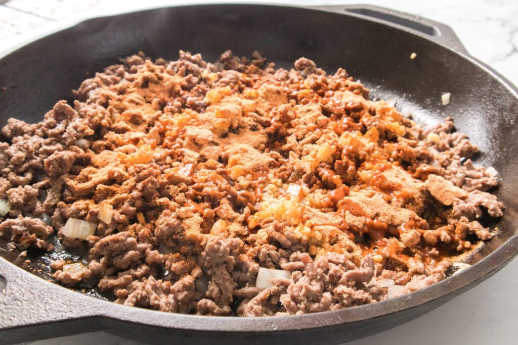 cast iron skillet with ground beef, onion and taco seasoning