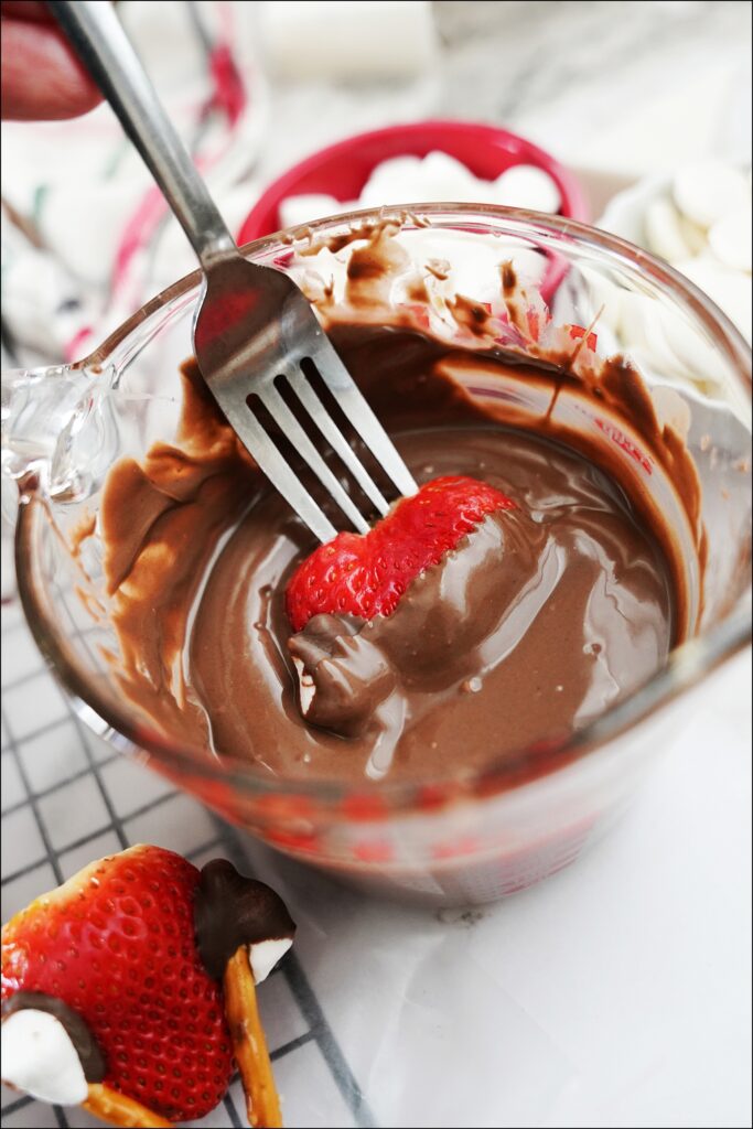 fork dipping strawberry into melted chocolate