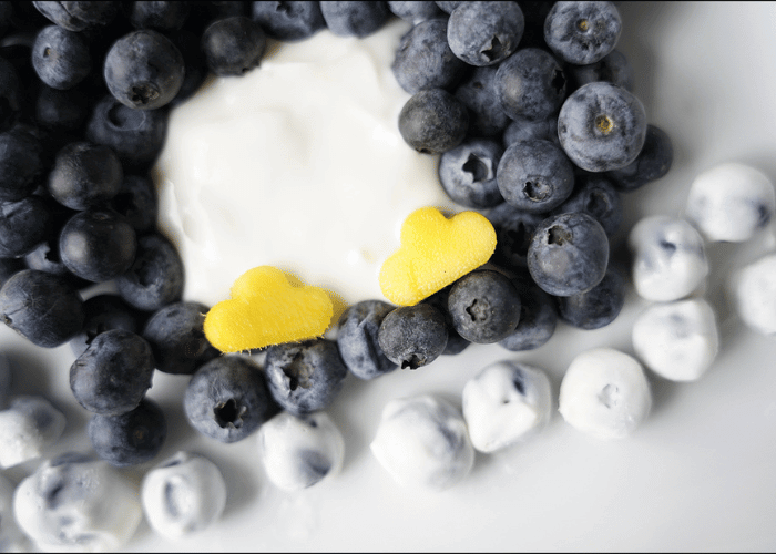 close up shot of blueberries with yogurt and mango with feet cut out with flower cookie cutter