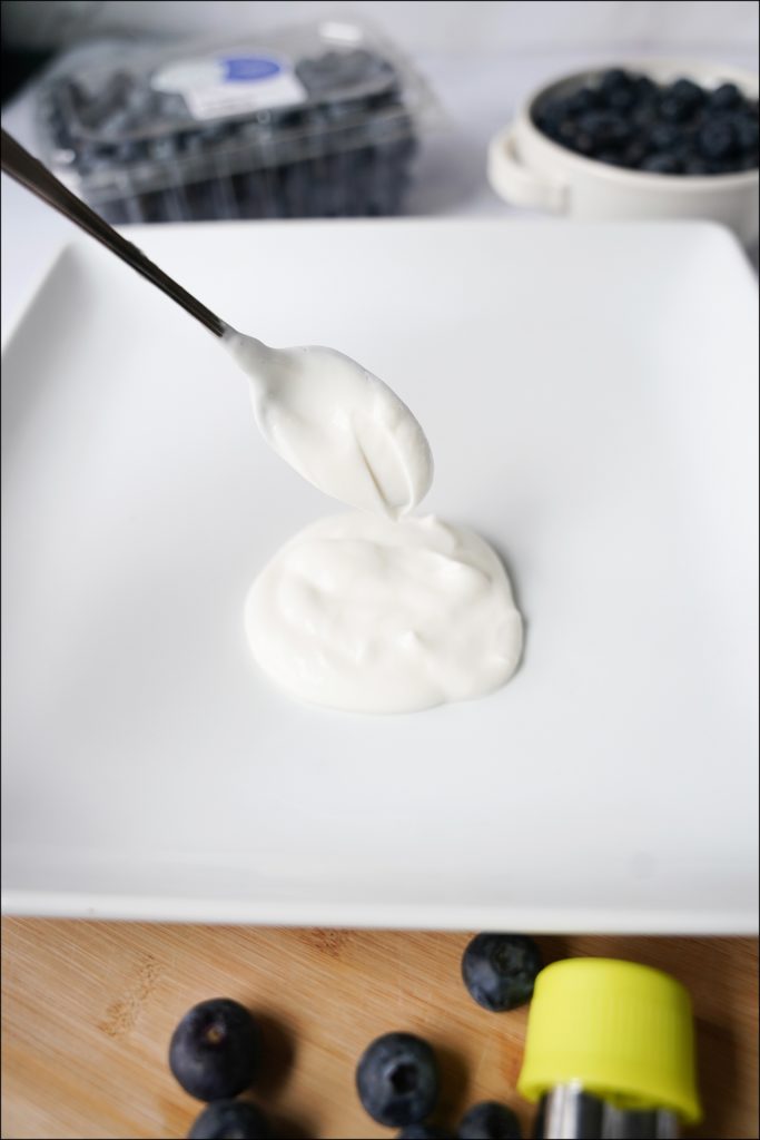 spoon with yogurt dolloping on white plate