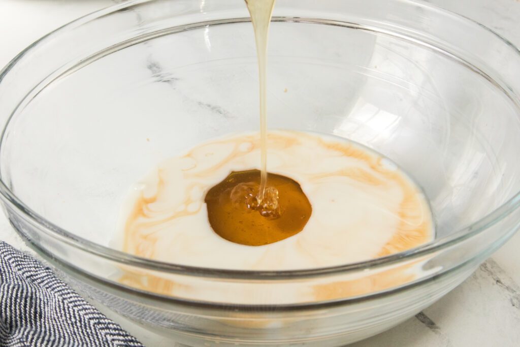 drizzling honey in a glass bowl with milk and olive oil