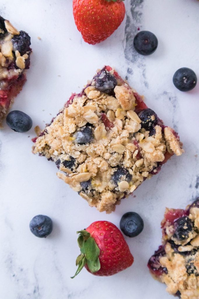 overhead shot of mixed berry crumble bars with blueberries and strawberries