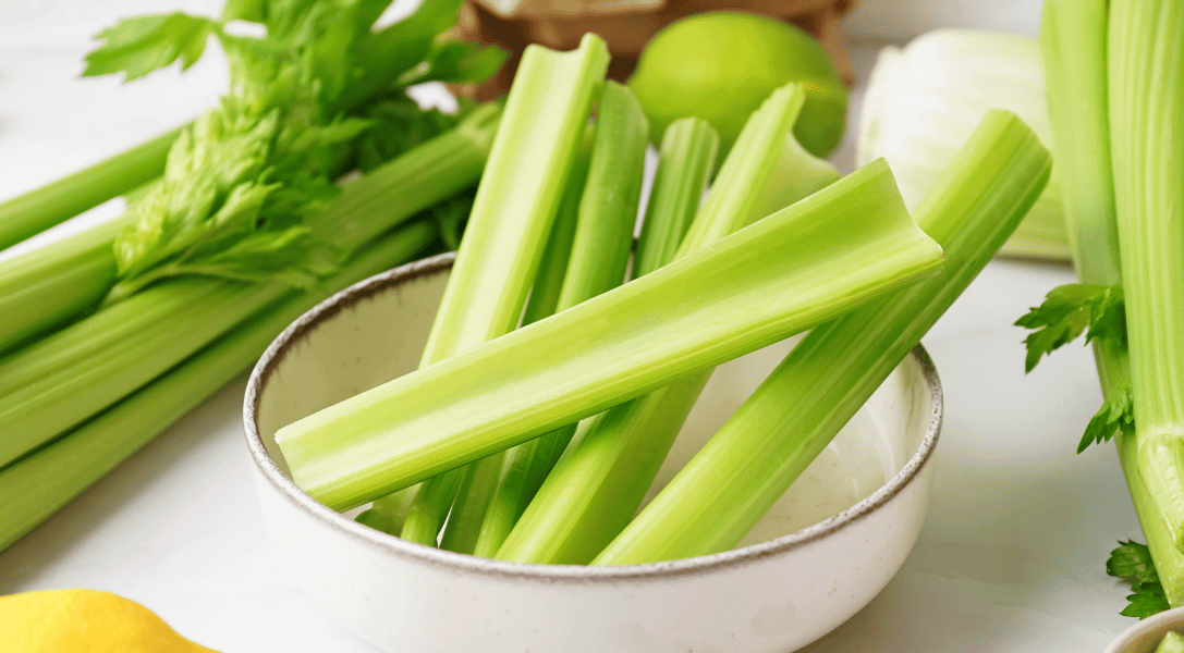 Celery sticks in a bowl with stalks of celery to the side
