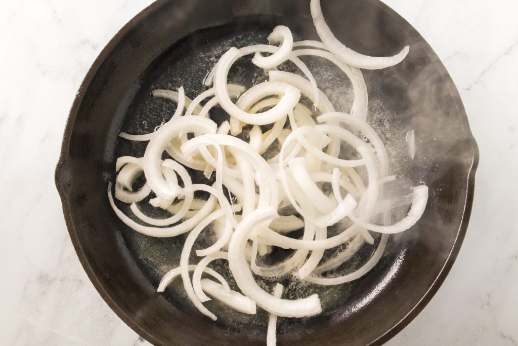 melted butter and sliced white onions caramelizing in cast iron skillet