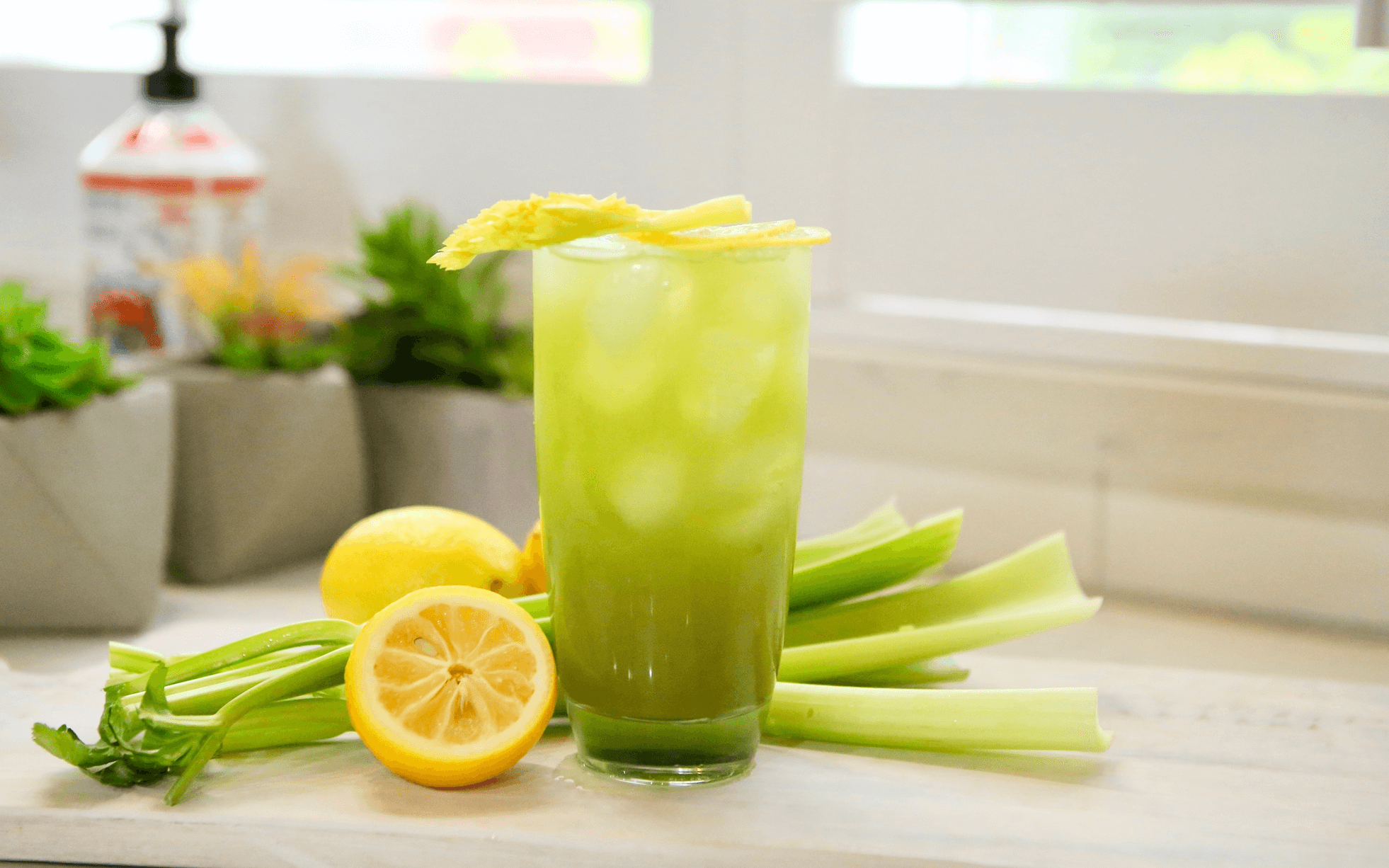 Dandy Celery Juice Matcha Lemonade with lemons and celery on counter
