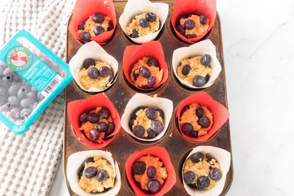unbaked blueberry muffins in muffin tin with red and white liners
