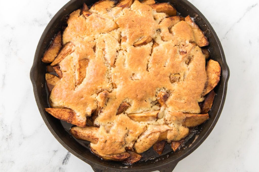 overhead shot of apple cobbler recipe after it's been baked in the oven in a cast iron skillet