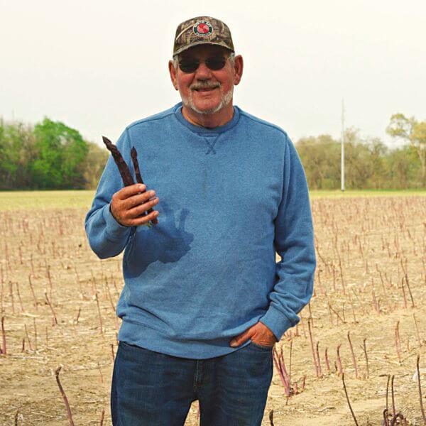 Ron Richter in asparagus field holding asparagus spears