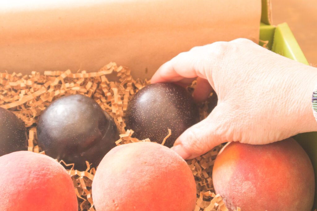 hand grabbing plum from the fruitful market box