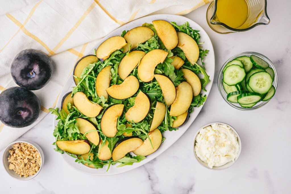 Slices of plums on plate of arugula