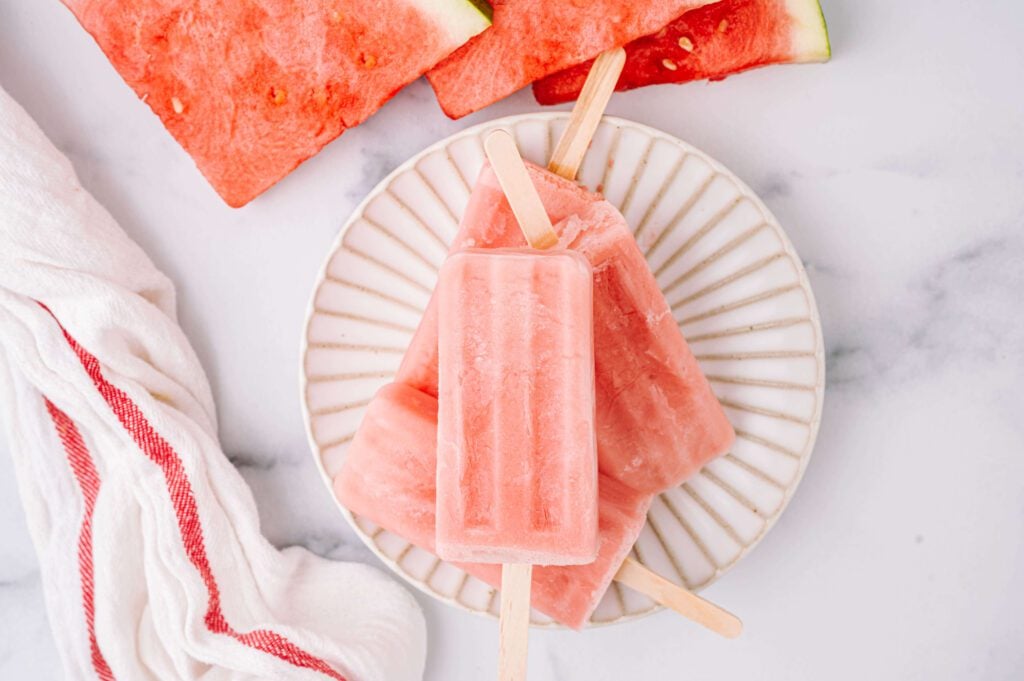 horizontal image of stacked watermelon yogurt pops with watermelon slices