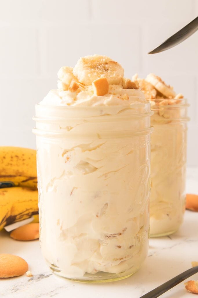 Banana pudding in mason jars with spoon in background