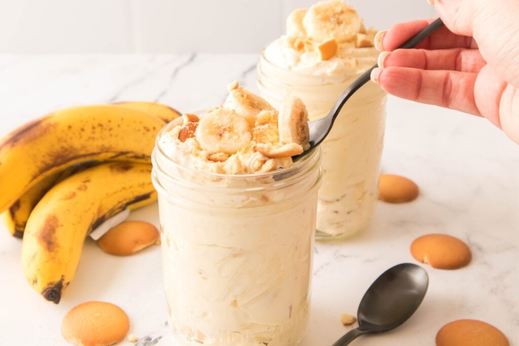 Finished Banana pudding in mason jars with bananas in background