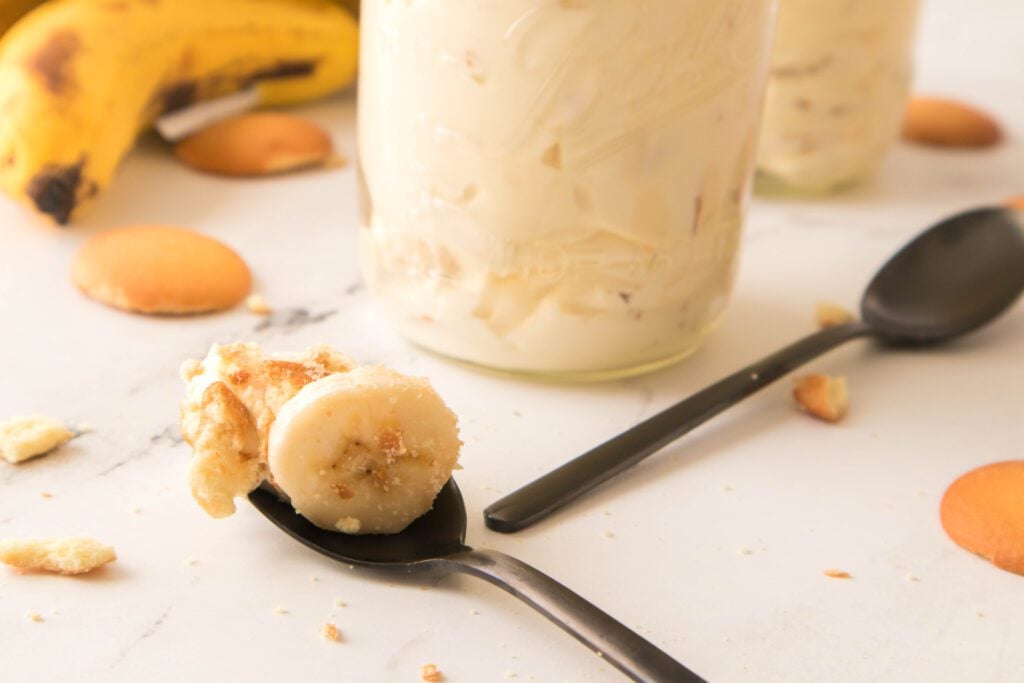 Spoonful of banana pudding with mason jars filled in the background