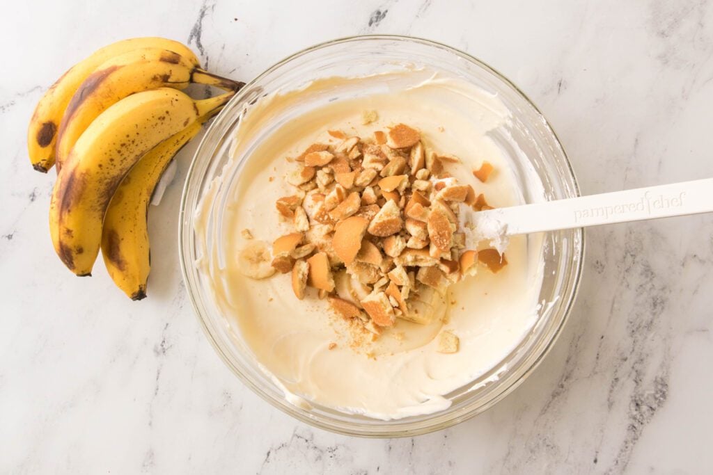 Folding in the sliced bananas and crushed wafers into the mixture