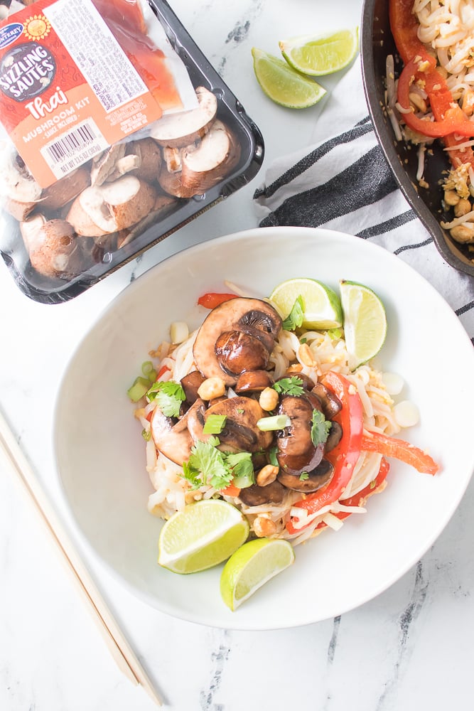 overhead shot of mushroom pad thai in white bowl topped with mushrooms