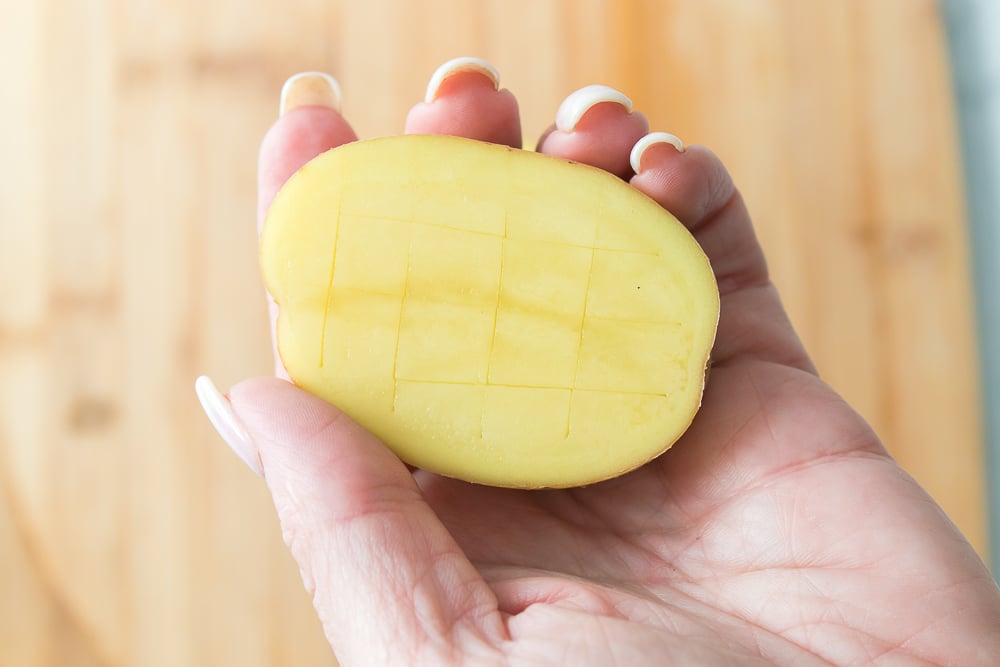 hand holding a potato that has been scored